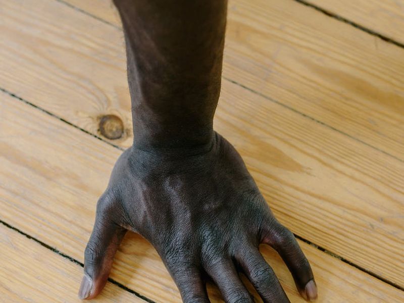 Close-up of a man's hands gripping the floor during a push-up, showing focus.